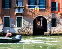 Venice drive through A man in a boat driving over the canals of Venice. In the background is a typical city scene with colorfull walls and windows in long exposure.